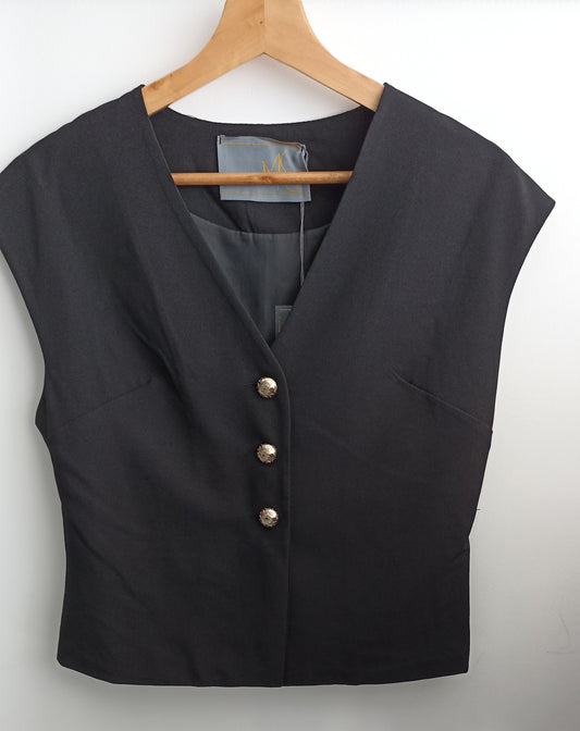 Front of the black MS Station waistcoat on a wooden hanger, showing a V-neckline and three metallic buttons.