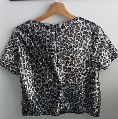 Back of the Michael Kors animal-print sequined crop top on a hanger, showing the centre-back zip.