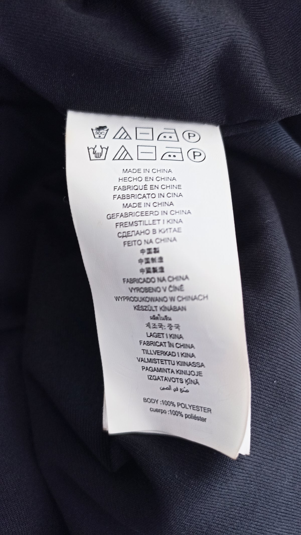 Michael Kors top care label showing washing symbols, Made in China and 100% polyester body fabric.