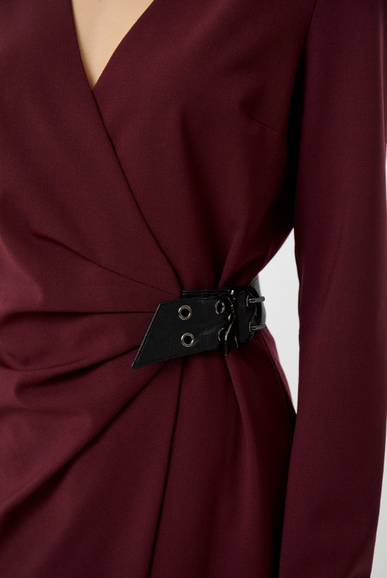 Close-up of the burgundy dress showing its V-neckline, gathered waist and black buckle with metal eyelets.