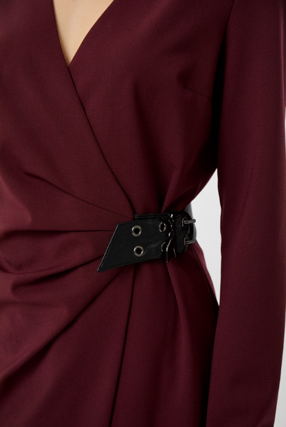 Close-up of the burgundy dress showing its V-neckline, gathered waist and black buckle with metal eyelets.