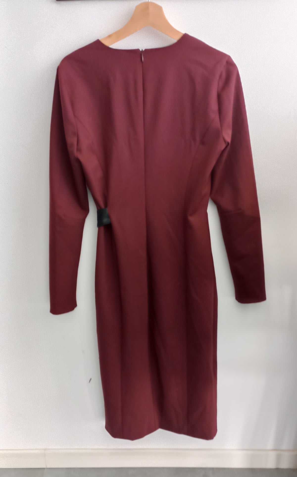 Back of the burgundy Patrizia Pepe dress on a wooden hanger, showing long sleeves and a centre-back zip.