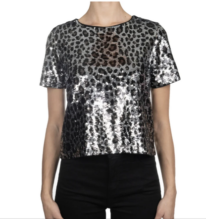 Front view of a model wearing the Michael Kors silver and black sequined short-sleeved crop top with black trousers.