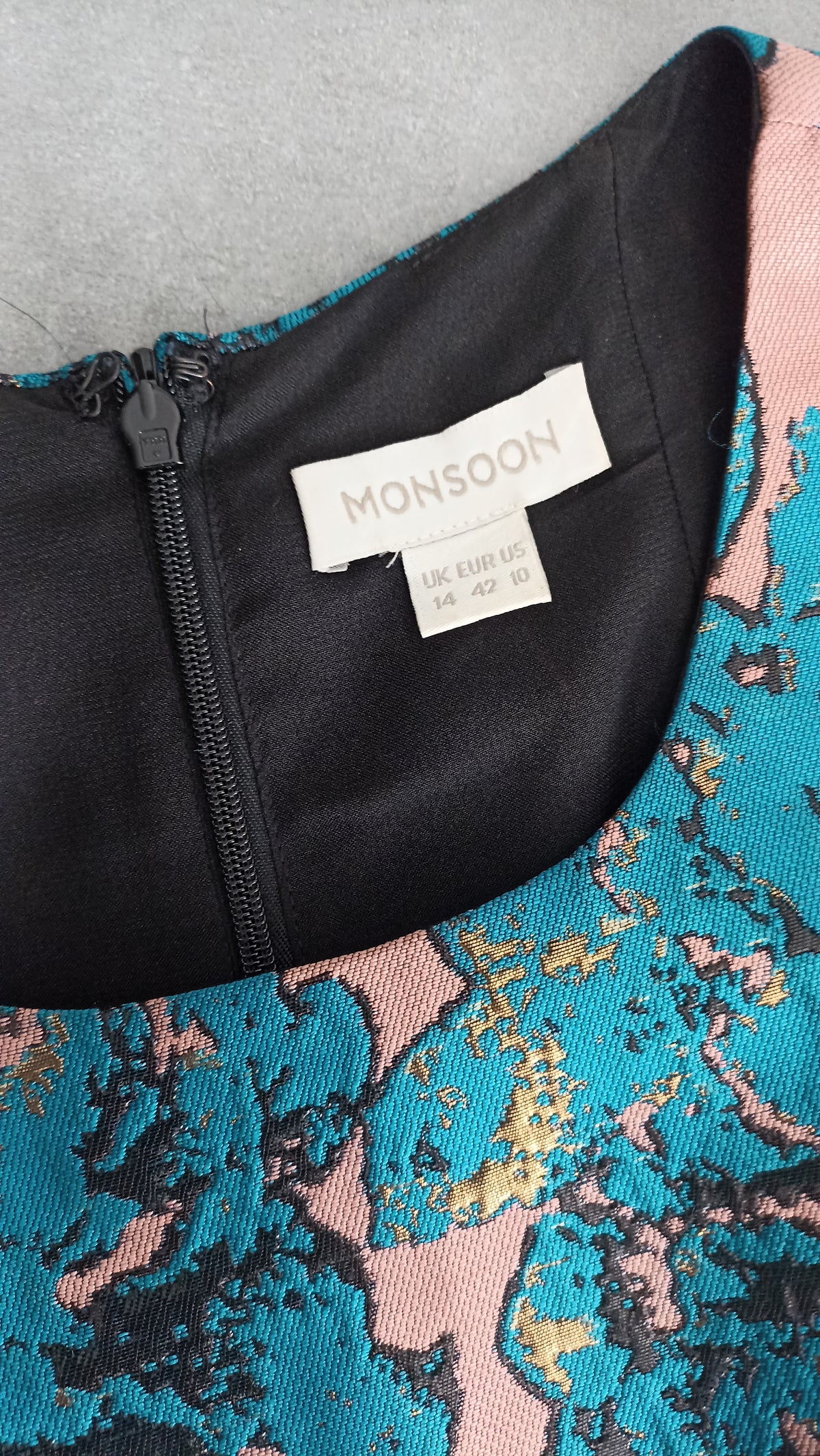 Monsoon brand and size labels showing UK 14, EUR 42 and US 10 beside the back zip and teal floral fabric.